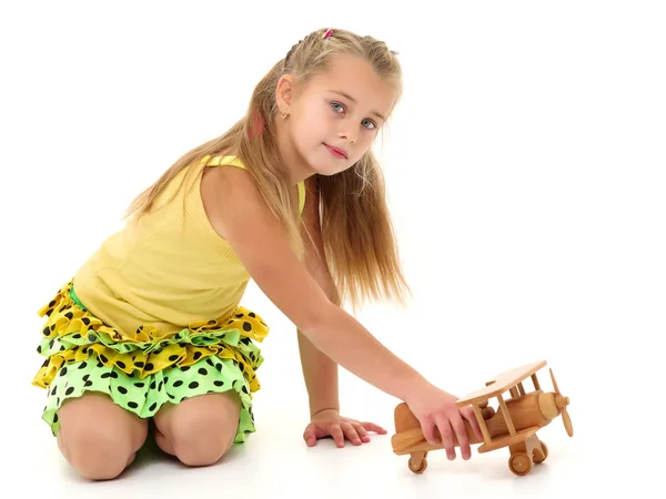 Klein meisje speelt met een houten vliegtuig. — Stockfoto