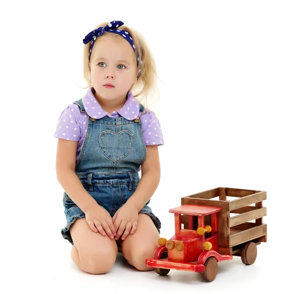 Κοριτσάκι παίζει με ένα ξύλινο αυτοκίνητο. — Φωτογραφία Αρχείου