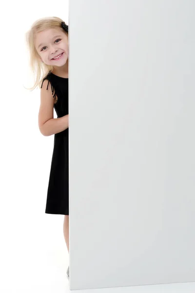 Una niña está mirando detrás de una pancarta vacía.. — Foto de Stock
