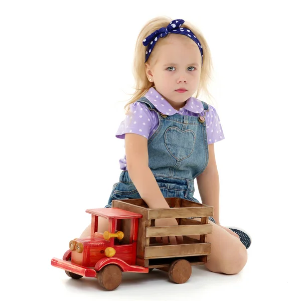 Menina está brincando com um carro de madeira . — Fotografia de Stock