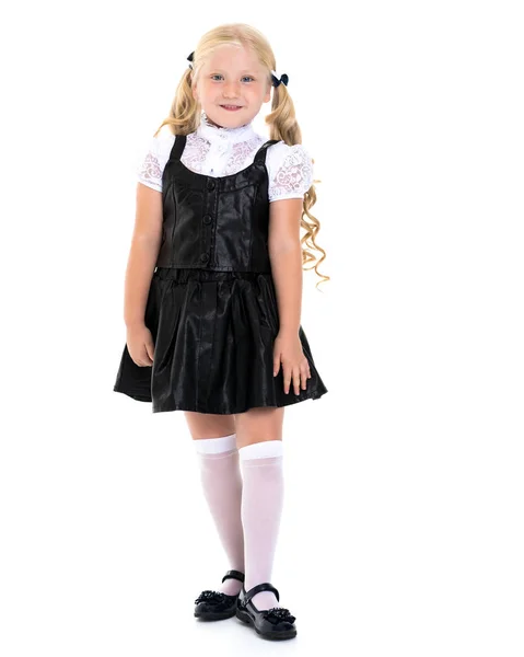 Vacker liten flicka i en skoluniform. Stockfoto