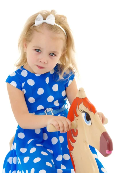 Girl swinging on a wooden horse. — Stock Photo, Image