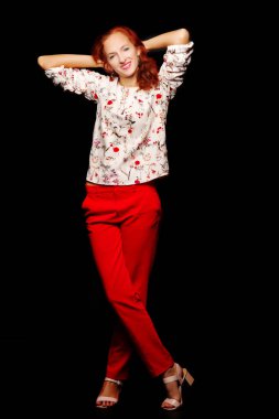 Stüdyoda siyah arka planda kızıl saçlı genç bir kadın..