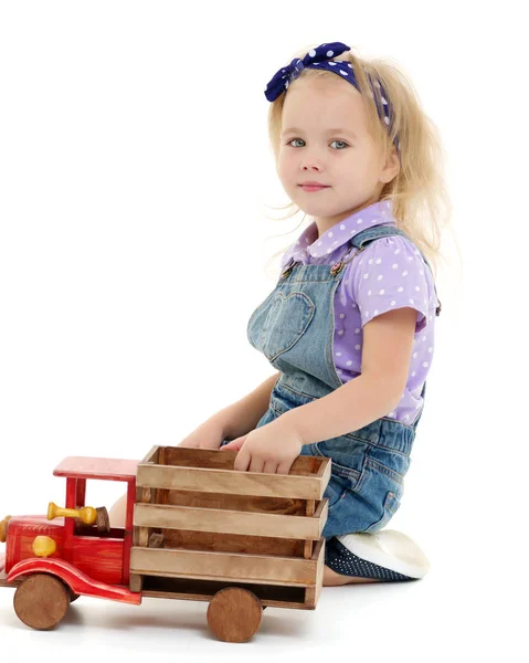 Little girl is playing with a wooden car. — Stock Photo, Image
