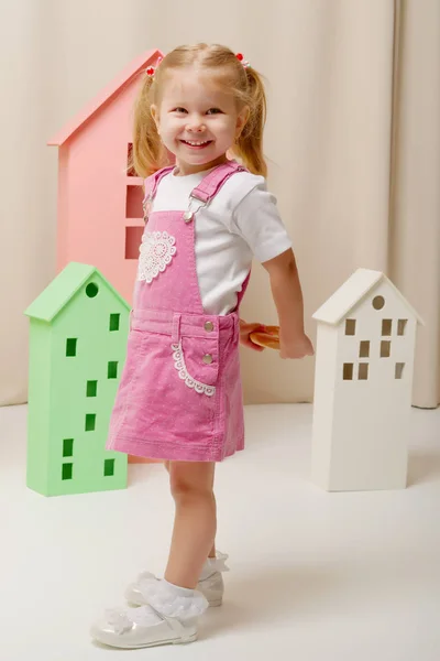 Kleines Mädchen spielt mit Holzhäusern. — Stockfoto