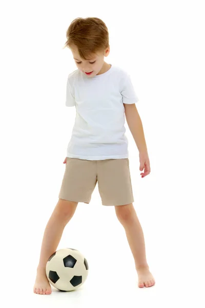En liten pojke som bär en ren vit t-shirt spelar med en fot — Stockfoto