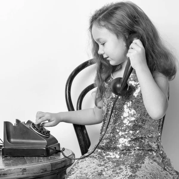 한 여자 애가 옛날 전화로 전화를 하고 있어. — 스톡 사진