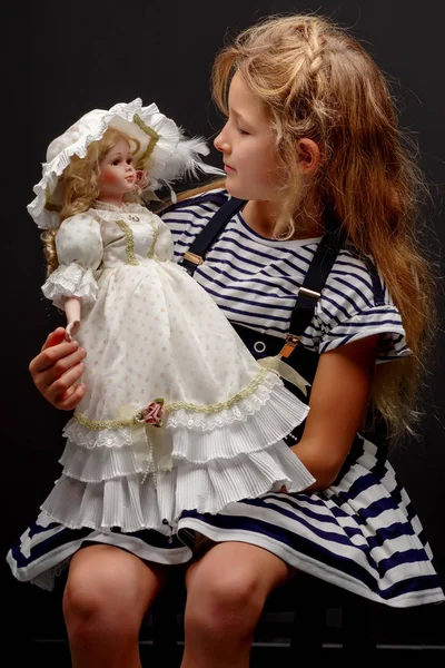 Маленькая девочка с куклой на черном фоне . — стоковое фото