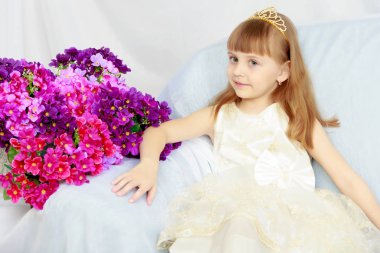 Kız bir buket çiçek yanında oturuyor.