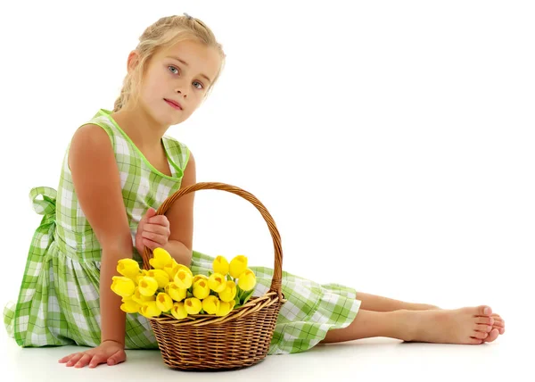 Schattig klein meisje met een mandje met bloemen. — Stockfoto