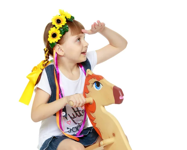 Маленькая девочка, качающаяся на деревянной лошади . — стоковое фото