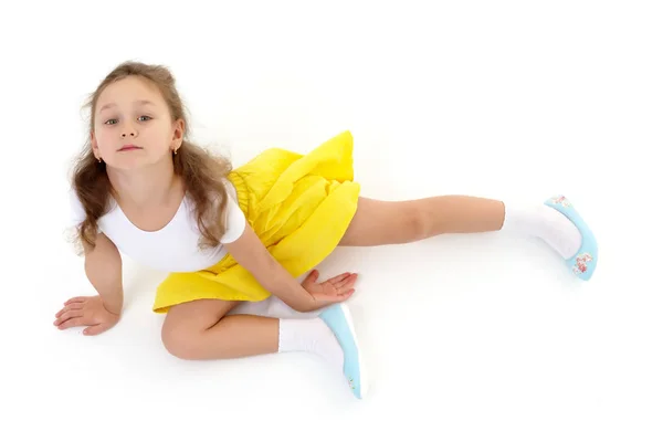 The little gymnast perform an acrobatic element on the floor.