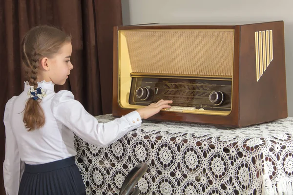 Little girl listens to old radio.