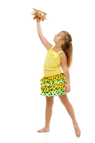 Little girl is playing with a wooden plane. — Stock Photo, Image