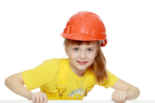 Chica en un casco de construcción asoma por detrás de una valla publicitaria . —  Fotos de Stock