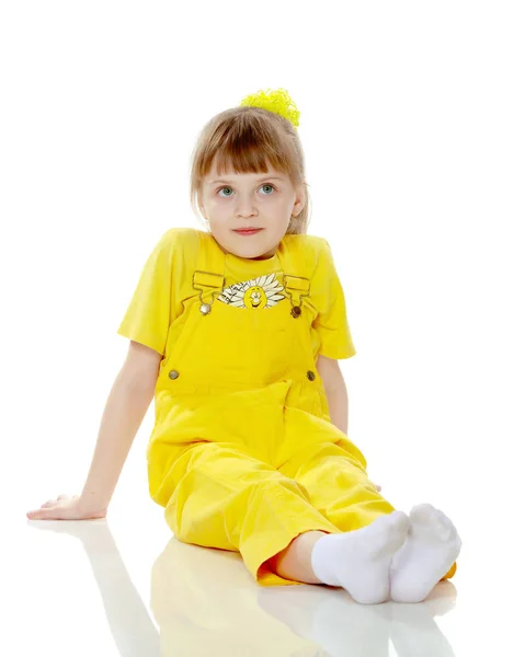 Chica con un flequillo corto en la cabeza y un mono amarillo brillante . — Foto de Stock