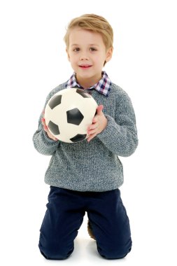 Küçük çocuk bir futbol topuyla oynuyor.