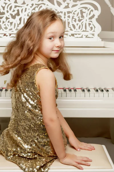 A menina está no piano de cauda branco. — Fotografia de Stock