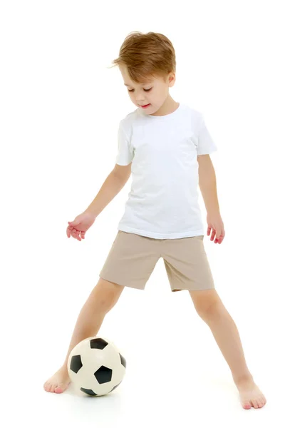 En liten pojke som bär en ren vit t-shirt spelar med en fot — Stockfoto