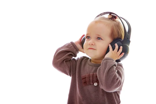 En liten flicka med hörlurar som lyssnar på musik. — Stockfoto