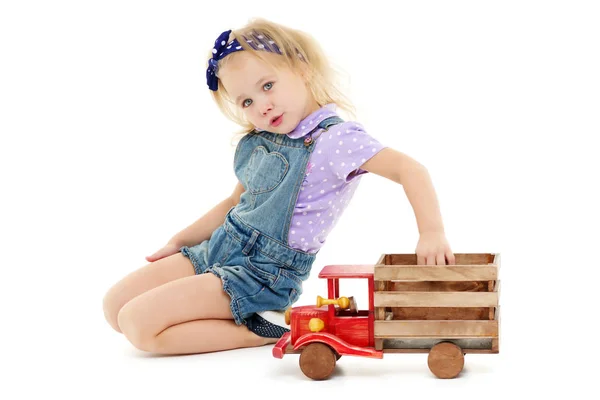 Little girl is playing with a wooden car. — Stock Photo, Image