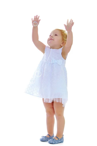 En liten flicka fångster såpbubblor. — Stockfoto