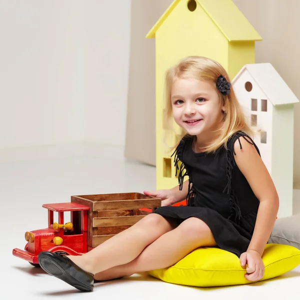 Meisje speelt met een houten auto. — Stockfoto