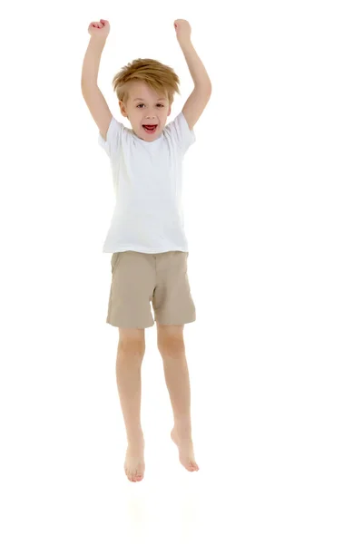 Ένα μικρό αγόρι σε ένα καθαρό άσπρο T-shirt είναι το άλμα διασκέδαση. — Φωτογραφία Αρχείου