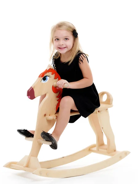 Menina balançando em um cavalo de madeira . — Fotografia de Stock