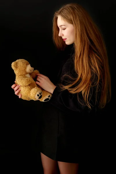 Adolescente con un oso de peluche sobre un fondo negro . —  Fotos de Stock