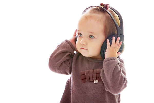 Маленькая девочка в наушниках слушает музыку. — стоковое фото