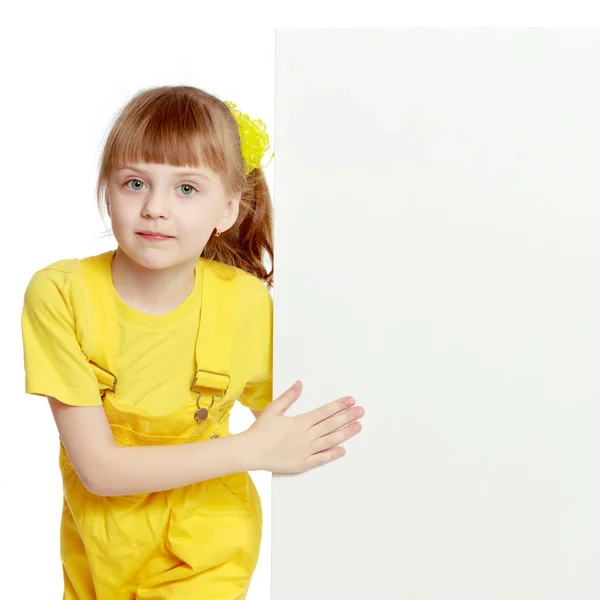 Girl with a short bangs on her head and bright yellow overalls. — Stock Photo, Image