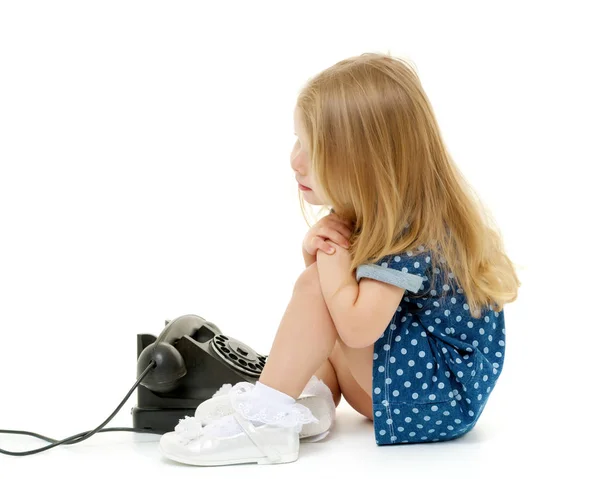 Malá holčička zvoní na starém telefonu. — Stock fotografie
