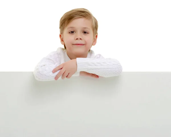 Un bambino guarda da dietro uno striscione vuoto . — Foto Stock