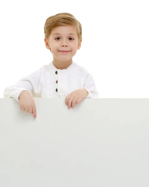 Un petit garçon regarde par derrière une bannière vide. — Photo