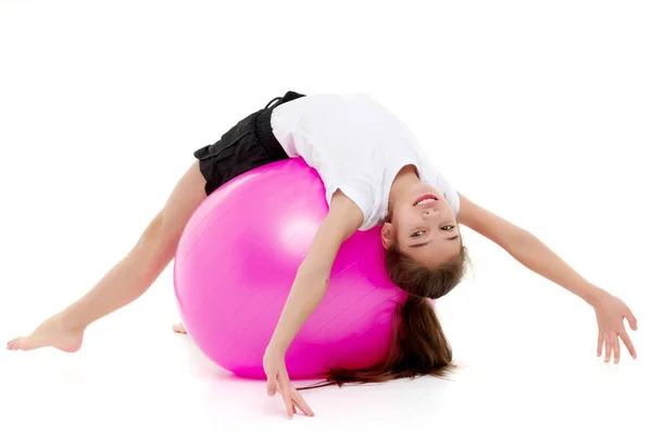 Liten flicka gör övningar på en stor boll för fitness. — Stockfoto