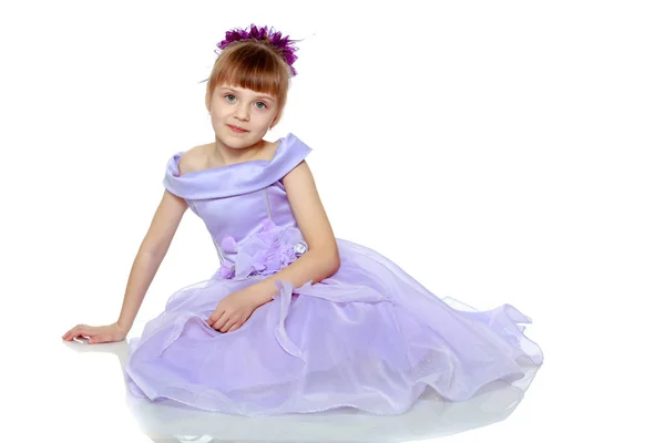 Girl sits on the floor with her hands folded in front of her. — Stock Photo, Image