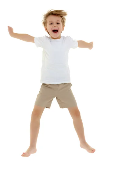 Ein kleiner Junge im sauberen weißen T-Shirt macht beim Springen Spaß. Stockbild