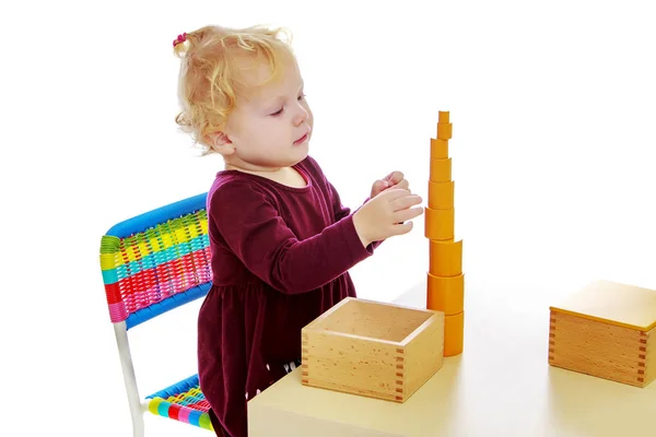 Das kleine Mädchen am Tisch arbeitet mit dem Montessori-Material. — Stockfoto