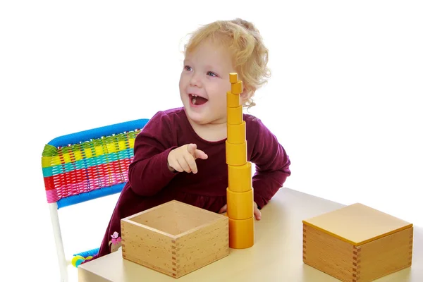 La petite fille à la table travaille avec le matériau Montessori . — Photo