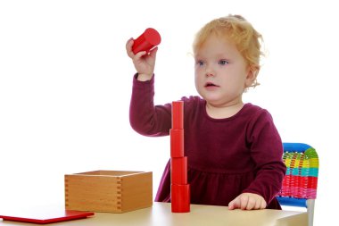 Masada küçük kız Montessori malzemesi ile çalışıyor.