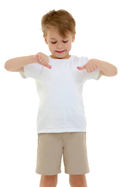 Un niño pequeño con una camiseta blanca pura la señala con los dedos. — Foto de Stock