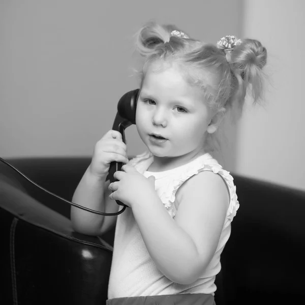 Uma menina está tocando no telefone antigo. — Fotografia de Stock