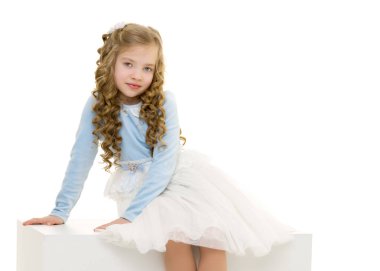 Küçük kız beyaz bir pankartta oturuyor..