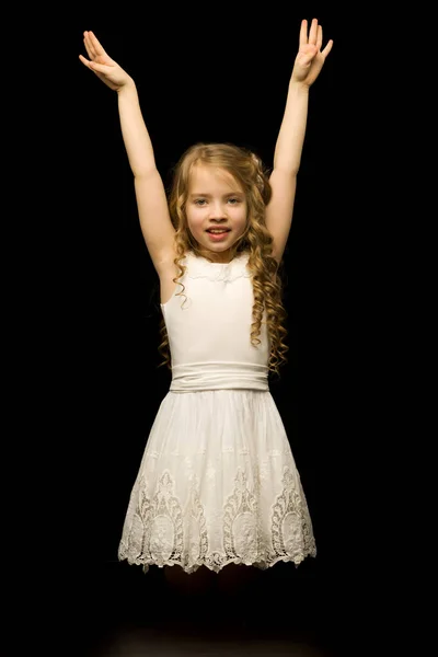 Uma menina está ajoelhada em um fundo preto no estúdio. — Fotografia de Stock