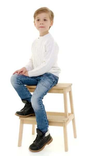 En liten pojke sitter på en stol. — Stockfoto