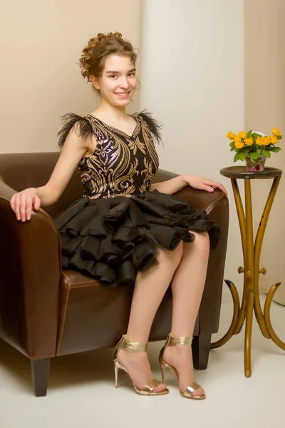 Teenager Mädchen in elegantem Kleid sitzt auf der Couch. — Stockfoto