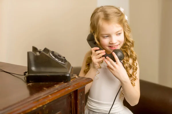 A little girl is ringing on the old phone. — Stock Photo, Image