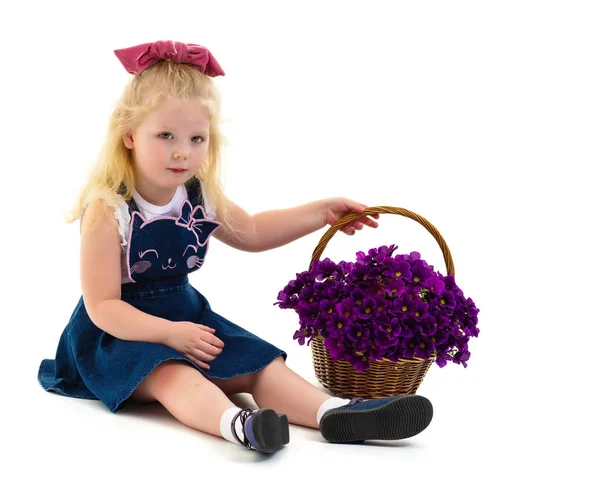 Schattig klein meisje met een mandje met bloemen. — Stockfoto