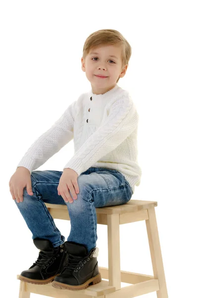 Un niño pequeño está sentado en una silla . —  Fotos de Stock